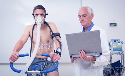 En mand laver en cykeltest (arbejds-EKG), og mens en læge følger med