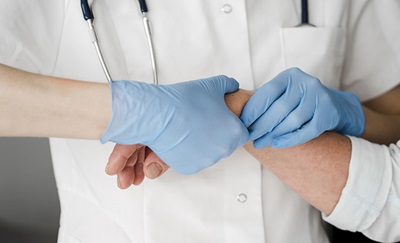 En læge undersøger en patient, for om personer har brug for en stivgørelse af håndleddet
