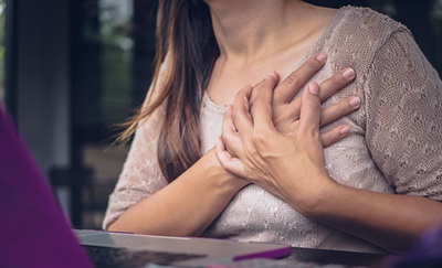 En kvinde holder sig til brystet på grund af hjertekramper