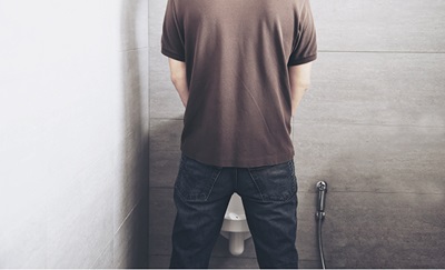 En mand med forstørret prostata står og urinerer