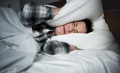 En mand holder en pude for ørene pga. søvnproblemer