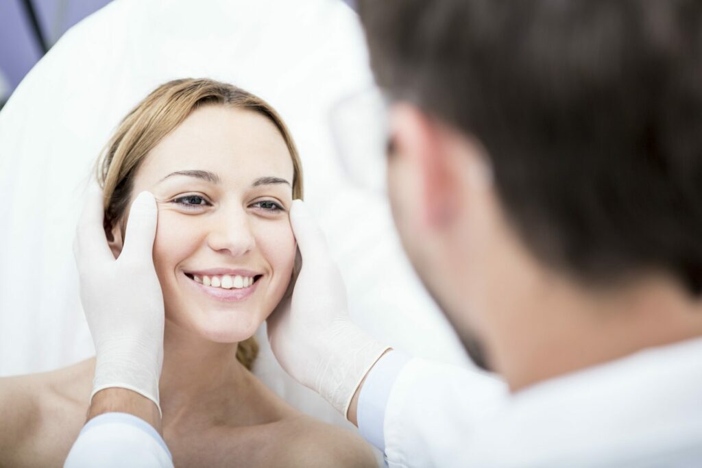 Plastikkirurgi læge kigger på en kvindes ansigt